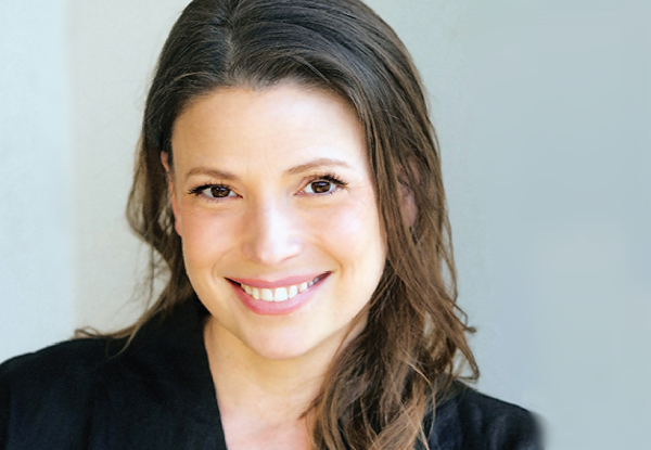 Portrait of a smiling woman with long hair and a black blouse.