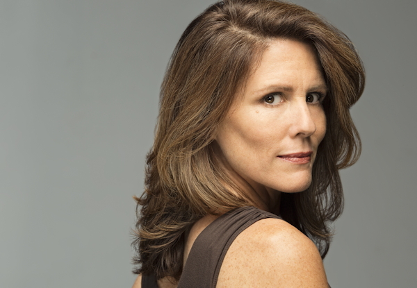 Middle-aged woman with shoulder-length brown hair, looking over her shoulder.