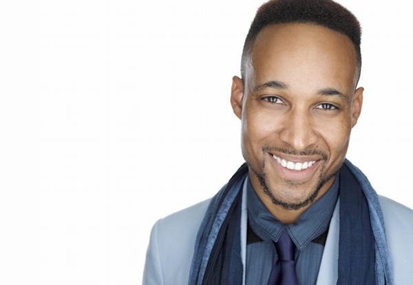 Smiling man in suit with tie and scarf against white background.