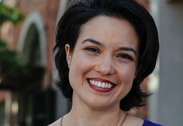 Smiling woman with short dark hair in an urban setting.