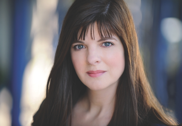 Portrait of a woman with long brown hair and bangs, looking at camera.