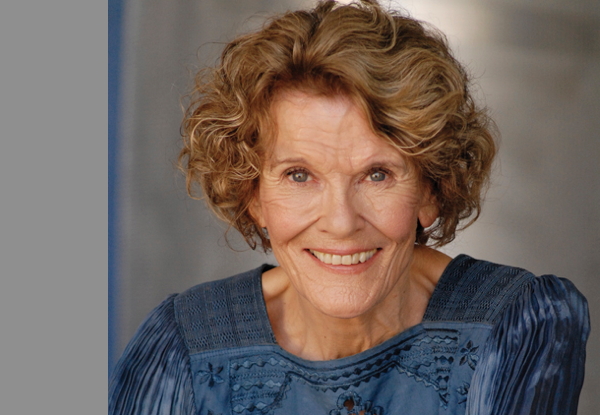Elderly woman smiling, wearing a blue blouse.