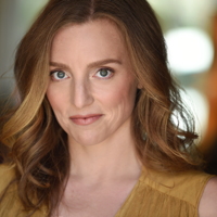 Woman with light brown hair and yellow top, smiling softly at the camera.