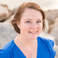 Woman in blue shirt smiling at the beach.