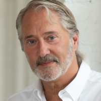 Portrait of an elderly man with a white beard and a white shirt.