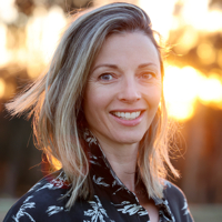 Woman smiling with sunset in background.