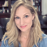 Portrait of a smiling blonde woman wearing a denim shirt, indoors.