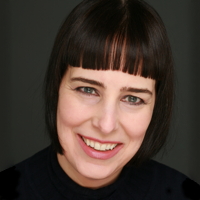 Woman with short black hair and bangs, smiling at the camera.