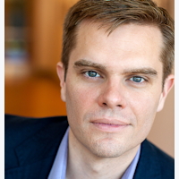 Close-up of a man with blue eyes wearing a blue shirt.