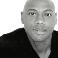 Black and white portrait of a bald man smiling at the camera.