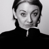 Black and white portrait of a woman with a raised eyebrow, resting chin on hand.