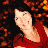Smiling woman in red top with a bokeh light background.