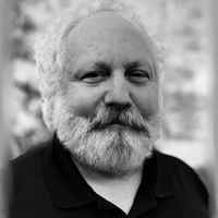 Black and white portrait of an older man with a beard smiling.