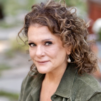 Portrait of a woman with curly hair wearing a green jacket.