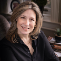 Portrait of a smiling woman with shoulder-length hair in a black shirt, indoors.