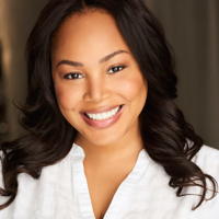 Portrait of a smiling woman with wavy hair wearing a white shirt.